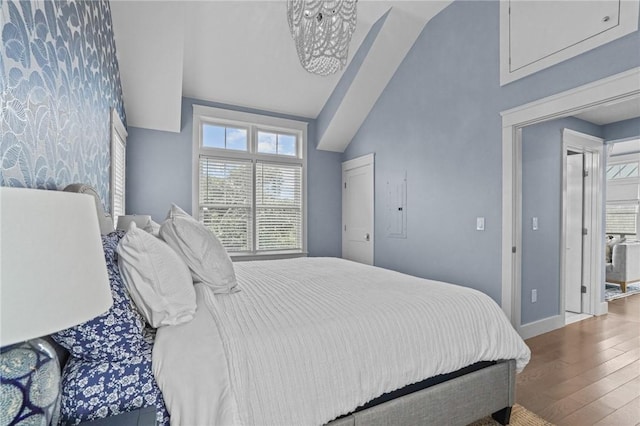 bedroom featuring hardwood / wood-style flooring, a notable chandelier, and vaulted ceiling