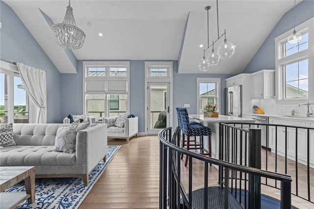 living room featuring hardwood / wood-style flooring, vaulted ceiling, sink, and a chandelier