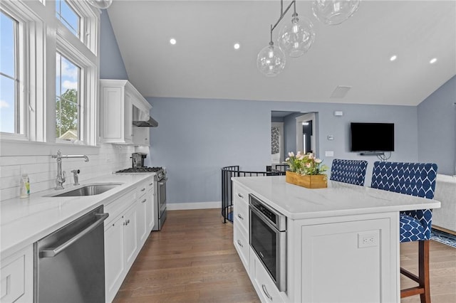 kitchen with appliances with stainless steel finishes, a breakfast bar, sink, a center island, and white cabinetry