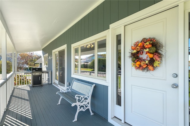 wooden deck featuring covered porch and a grill