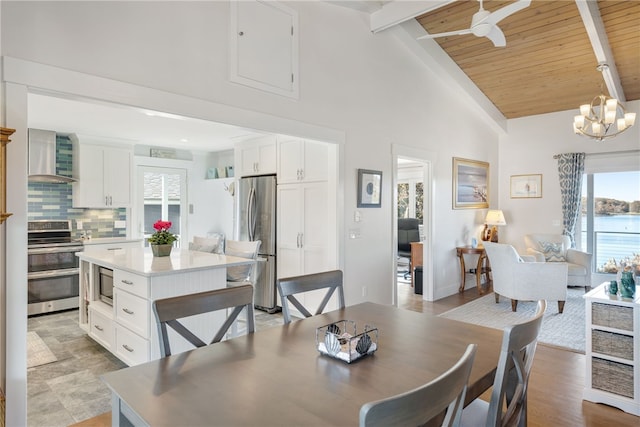 dining room with ceiling fan with notable chandelier, beam ceiling, wooden ceiling, and high vaulted ceiling