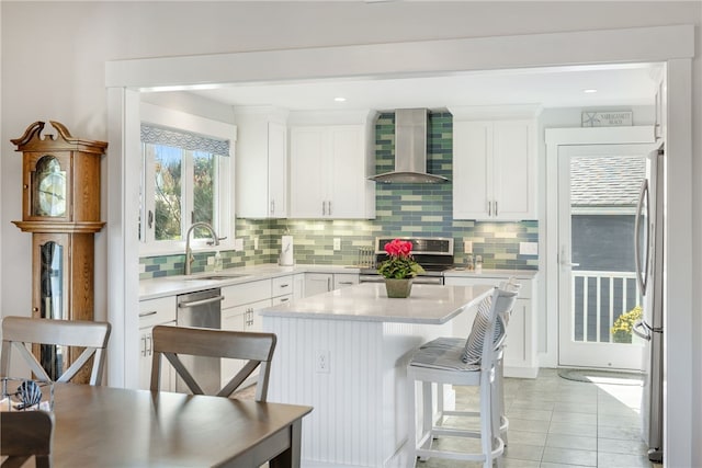 kitchen with white cabinets, sink, wall chimney exhaust hood, decorative backsplash, and appliances with stainless steel finishes