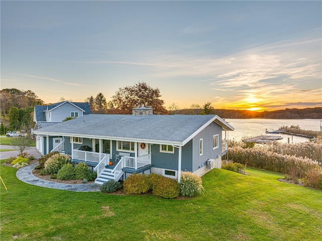 view of front facade featuring a yard, a water view, and covered porch