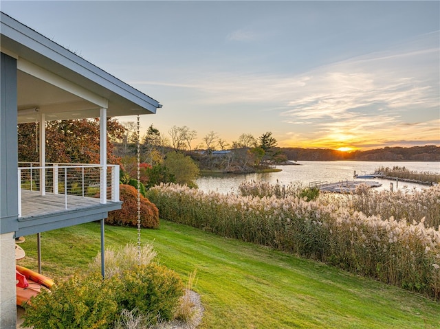 yard at dusk featuring a water view