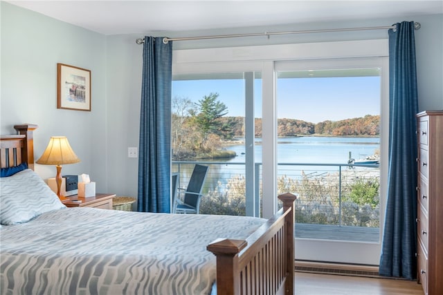 bedroom with a water view and hardwood / wood-style flooring