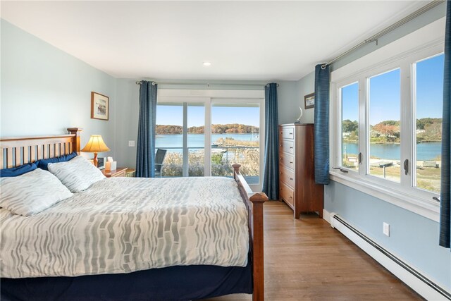 bedroom with a baseboard radiator, multiple windows, and a water view