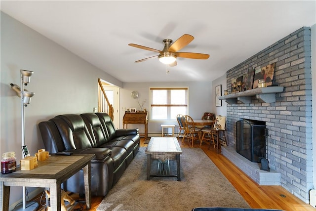 living room with hardwood / wood-style floors, ceiling fan, and a fireplace