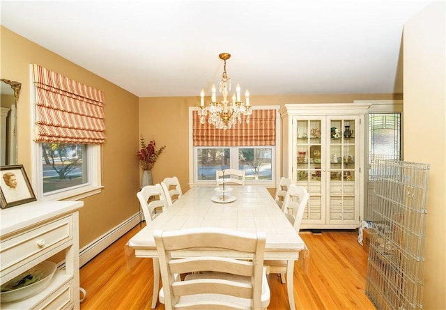 dining room featuring light hardwood / wood-style floors, an inviting chandelier, and baseboard heating