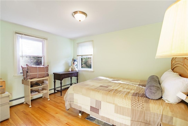 bedroom with light hardwood / wood-style flooring, multiple windows, and a baseboard radiator