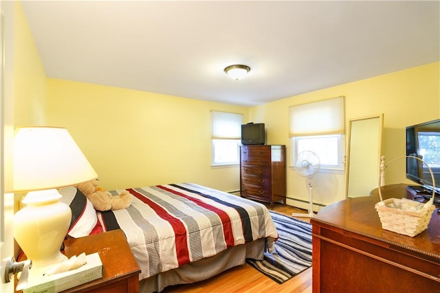 bedroom featuring light wood-type flooring and a baseboard heating unit