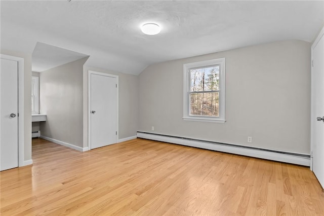 additional living space with baseboard heating, light hardwood / wood-style floors, and vaulted ceiling