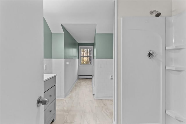 bathroom featuring vanity, a baseboard heating unit, and tile walls