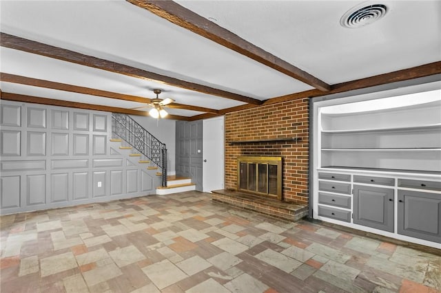 unfurnished living room featuring ceiling fan, built in shelves, a fireplace, and beamed ceiling