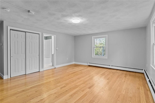 unfurnished bedroom featuring a baseboard radiator, a textured ceiling, and light hardwood / wood-style flooring