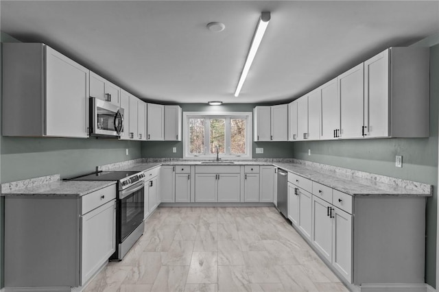 kitchen featuring white cabinetry, sink, light stone counters, and appliances with stainless steel finishes