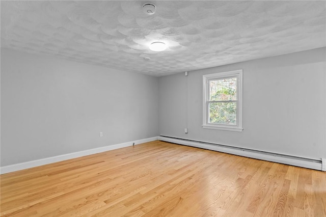 empty room featuring light hardwood / wood-style floors, a textured ceiling, and a baseboard heating unit