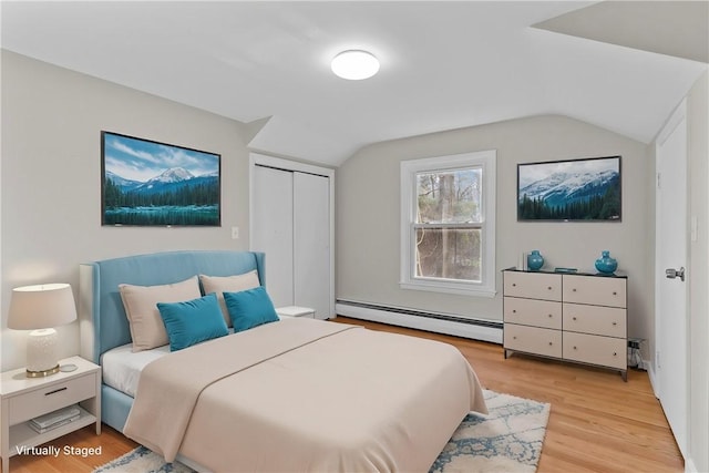 bedroom with a baseboard radiator, lofted ceiling, light hardwood / wood-style floors, and a closet