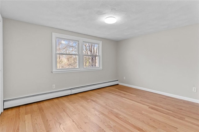 spare room with a baseboard radiator, a textured ceiling, and light hardwood / wood-style flooring