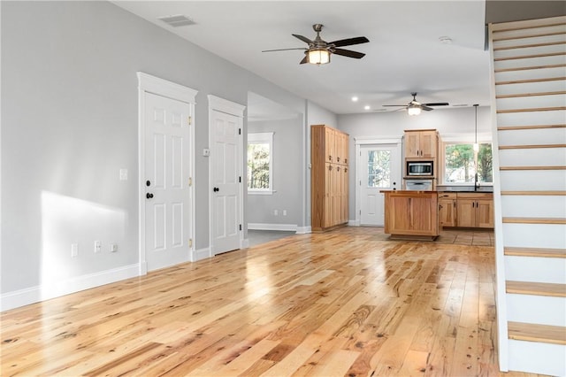 unfurnished living room with light wood-type flooring and ceiling fan