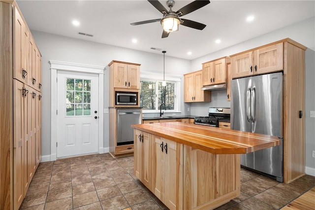 kitchen with ceiling fan, light brown cabinetry, decorative light fixtures, a kitchen island, and stainless steel appliances