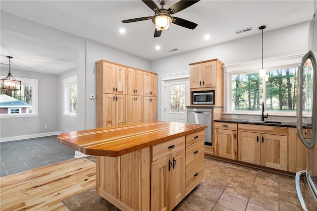 kitchen featuring light brown cabinets, sink, appliances with stainless steel finishes, butcher block countertops, and decorative light fixtures