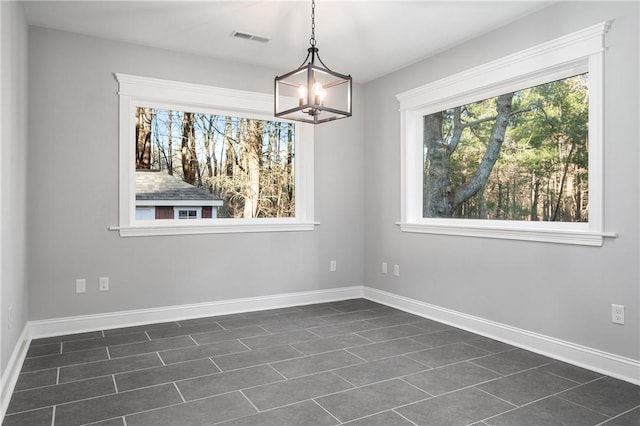 unfurnished dining area with dark tile patterned flooring and an inviting chandelier