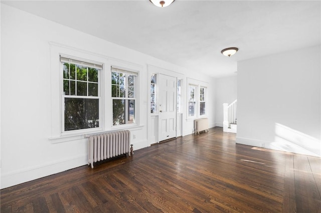 unfurnished room featuring radiator heating unit and dark hardwood / wood-style floors