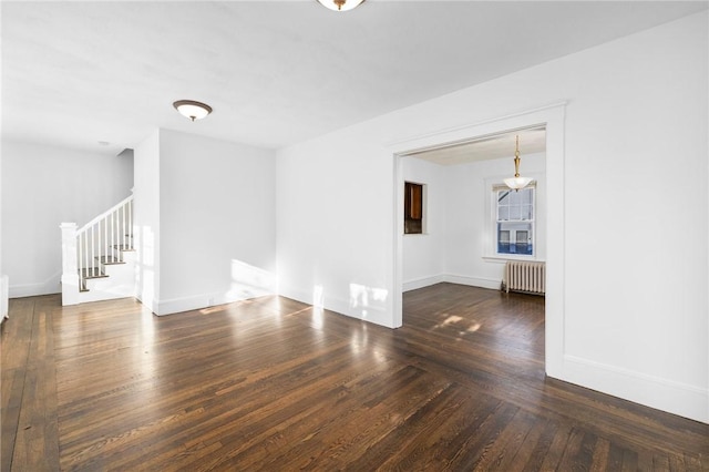 spare room with radiator heating unit and dark wood-type flooring