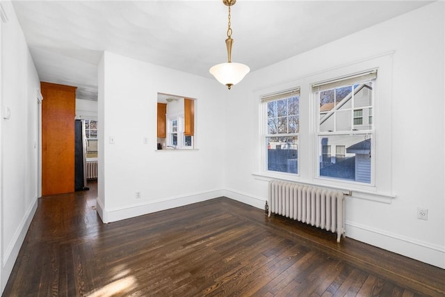 empty room with radiator heating unit and dark hardwood / wood-style floors