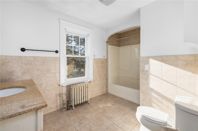 full bathroom with vanity, tile walls, tile patterned flooring, radiator heating unit, and toilet