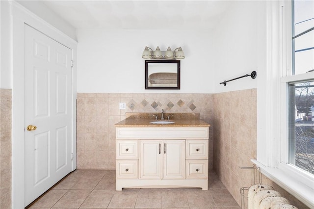 bathroom featuring radiator, vanity, a healthy amount of sunlight, and tile walls