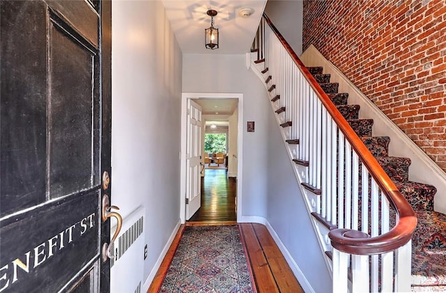 entryway with hardwood / wood-style flooring, radiator, and brick wall