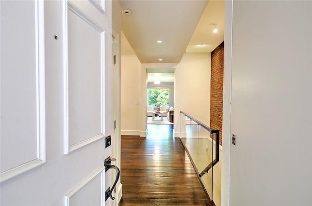 hallway with dark hardwood / wood-style flooring and brick wall