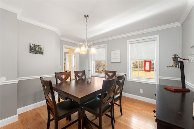 dining area with crown molding, a notable chandelier, and light wood-type flooring