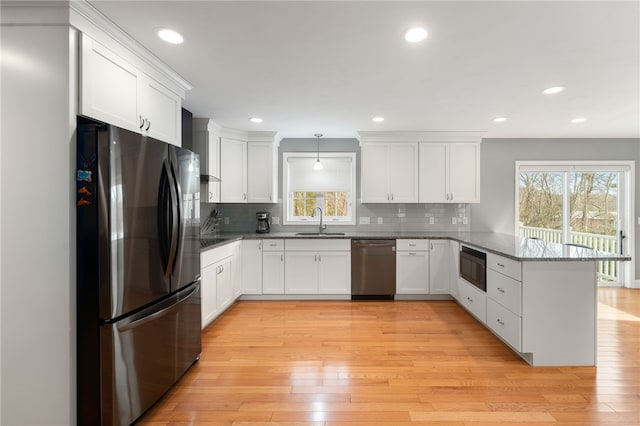 kitchen with kitchen peninsula, white cabinetry, hanging light fixtures, and appliances with stainless steel finishes