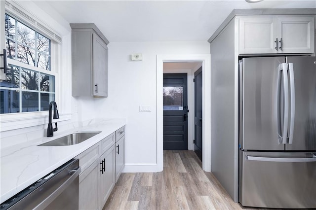 kitchen featuring gray cabinetry, light stone countertops, sink, and appliances with stainless steel finishes