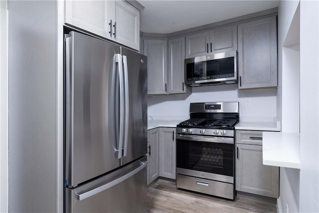 kitchen with stainless steel appliances, light hardwood / wood-style flooring, and gray cabinetry