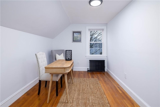 living area featuring hardwood / wood-style flooring, radiator, and vaulted ceiling