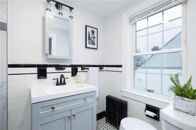 bathroom featuring toilet, radiator heating unit, and tile walls