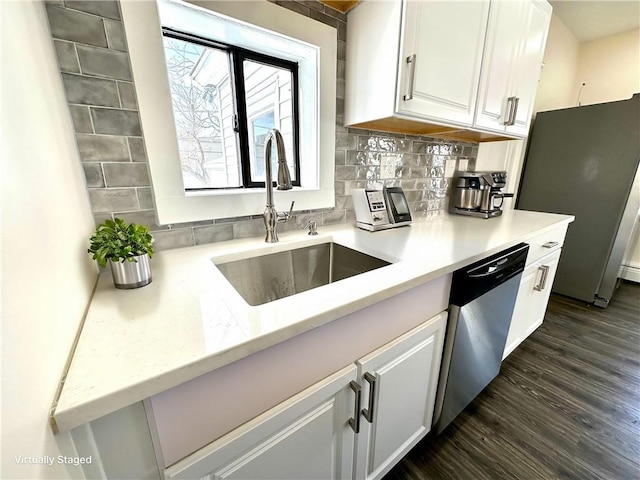 kitchen with dark wood-type flooring, sink, decorative backsplash, appliances with stainless steel finishes, and white cabinetry