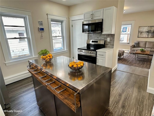 kitchen with backsplash, white cabinetry, stainless steel range, and a baseboard heating unit