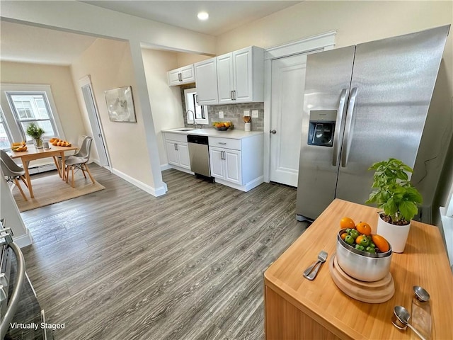 kitchen with tasteful backsplash, stainless steel appliances, sink, white cabinets, and light hardwood / wood-style floors