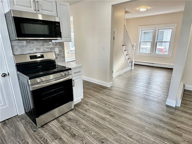 kitchen with backsplash, a wealth of natural light, a baseboard radiator, white cabinetry, and stainless steel appliances