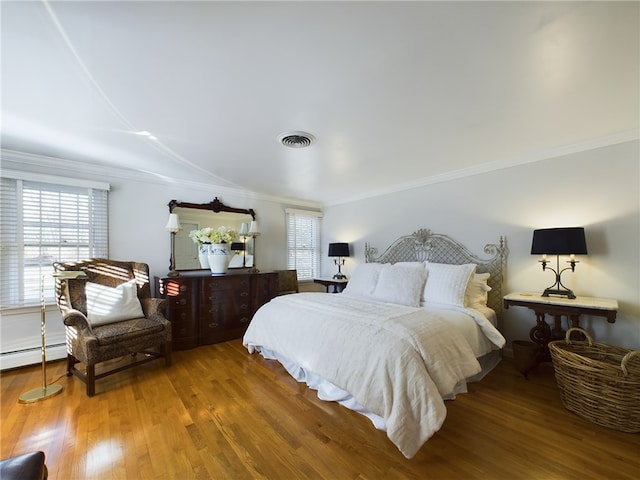 bedroom with a baseboard heating unit, wood-type flooring, ornamental molding, and multiple windows