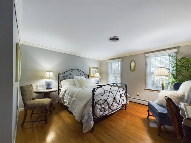 bedroom featuring baseboard heating, hardwood / wood-style flooring, and ornamental molding