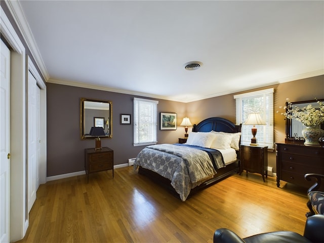 bedroom featuring multiple windows, crown molding, and hardwood / wood-style flooring