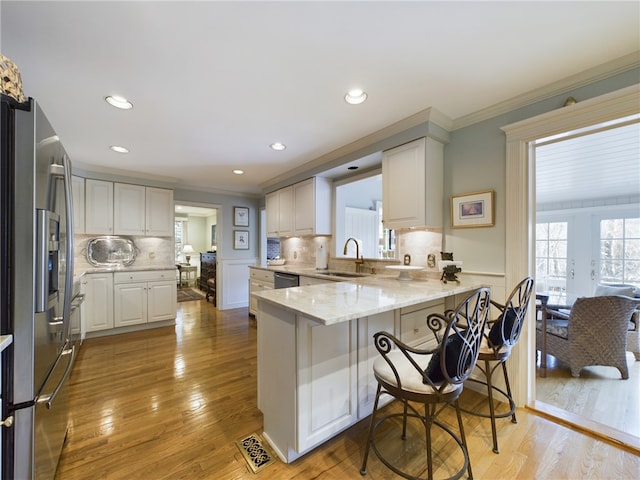 kitchen featuring backsplash, sink, kitchen peninsula, white cabinetry, and stainless steel appliances