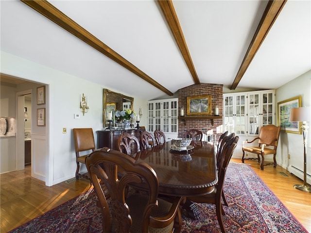 dining area featuring lofted ceiling with beams, a baseboard radiator, and light hardwood / wood-style flooring