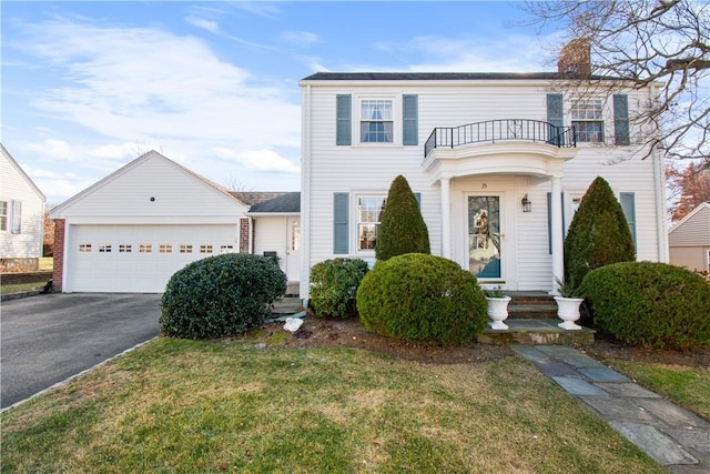 view of front of house featuring a garage, a balcony, and a front lawn