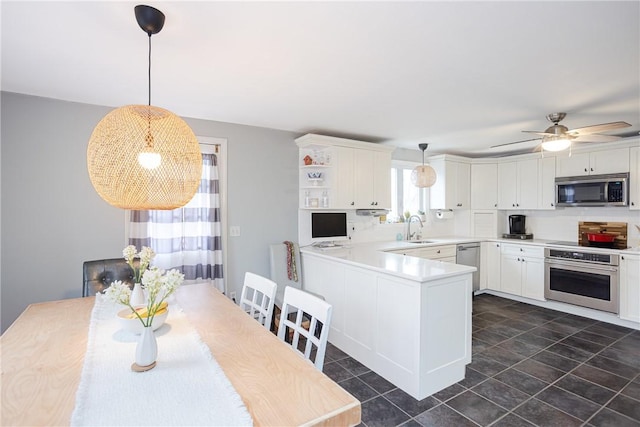 kitchen featuring kitchen peninsula, appliances with stainless steel finishes, sink, pendant lighting, and white cabinets